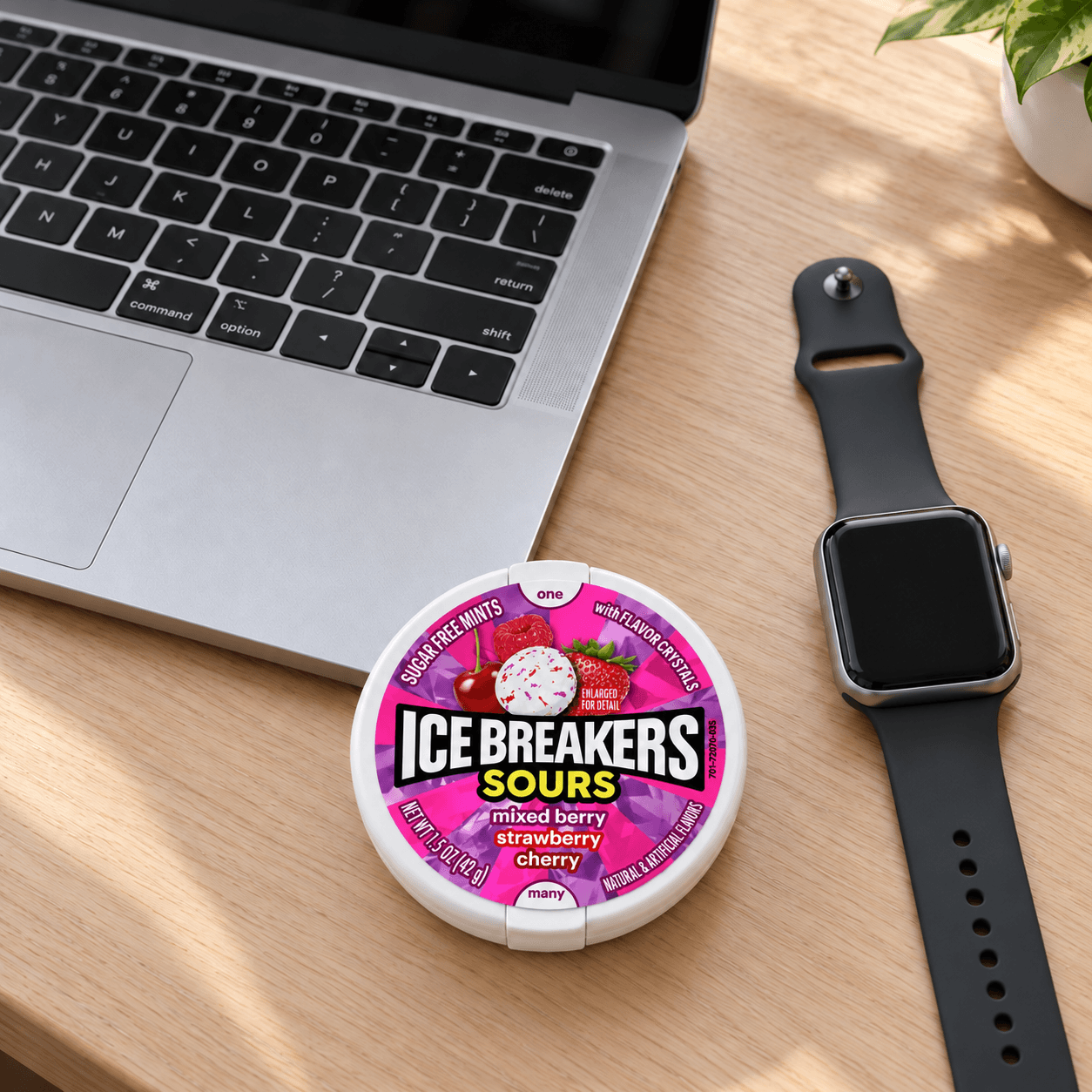 Кутия ICE BREAKERS Sours Mixed Berry 42 g върху дървено бюро до лаптоп и смартчасовник
